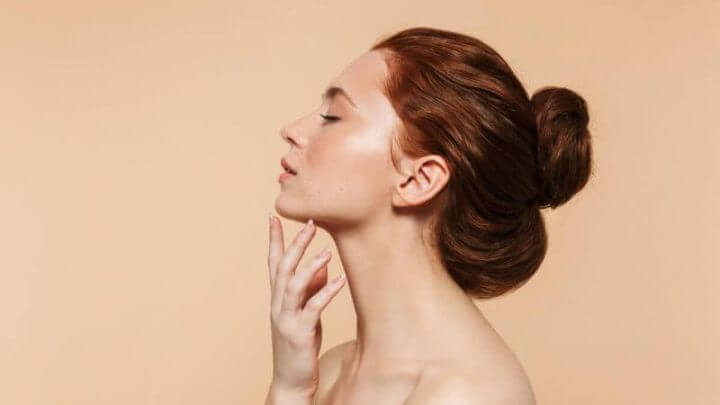 Mulher ruiva de perfil com a mão no rosto