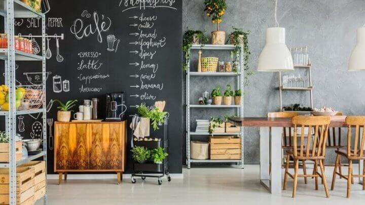 Sala com lousa na parede, móveis de madeira e estante com plantas