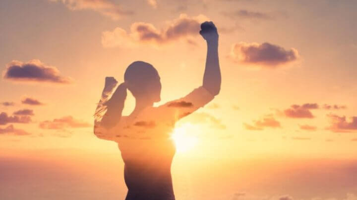 Mulher flexionando os braços no ar, sentindo-se motivada, conceito de força e coragem.