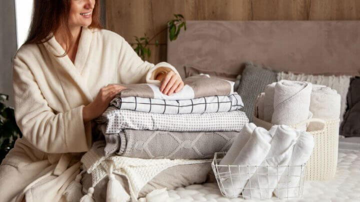 A mulher sentada e dobrando a roupa de cama