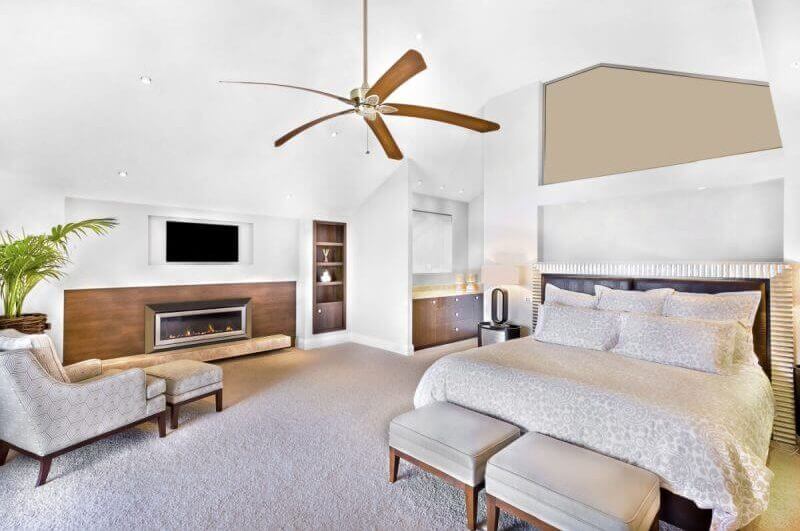 Quarto moderno, com parede clara, incluindo móveis, televisão anexada à parede, uma cadeira perto de vaso de flores, ventilador no teto, mesa de lâmpada