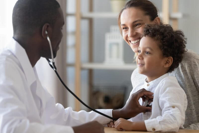Médico pediatra atendendo criança no colo da mãe