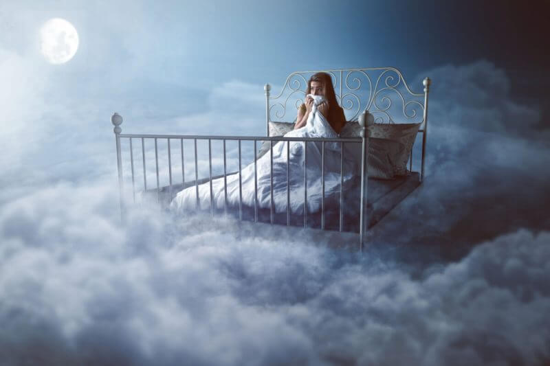 Mulher acordada e com medo nas nuvens; conceito de pesadelo