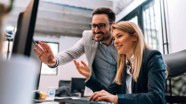 Homem e mulher em ambiente de trabalho analisando dados no computador