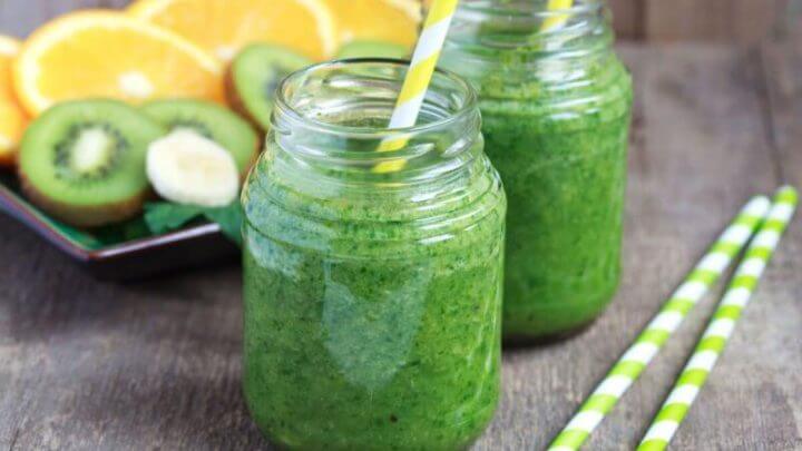 Copos de vidro com suco verde e canudo branco e amarelo