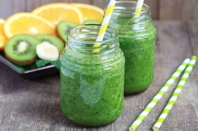 Copos de vidro com suco verde e canudo branco e amarelo