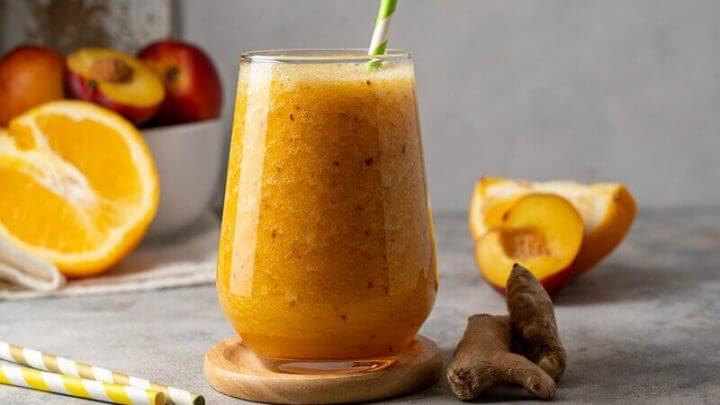 Copo de vidro com suco de pêssego, laranja e gengibre