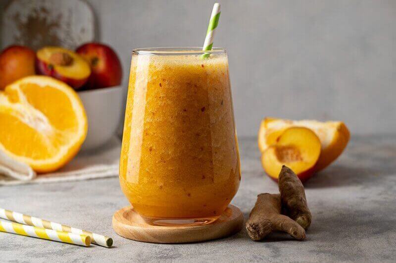 Copo de vidro com suco de pêssego, laranja e gengibre