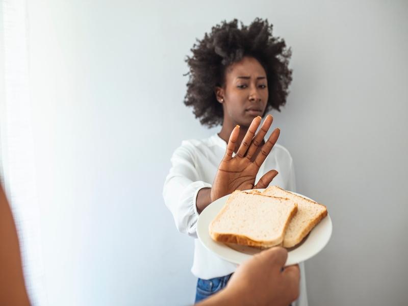 Mulher recusando fatias de pão com a mão