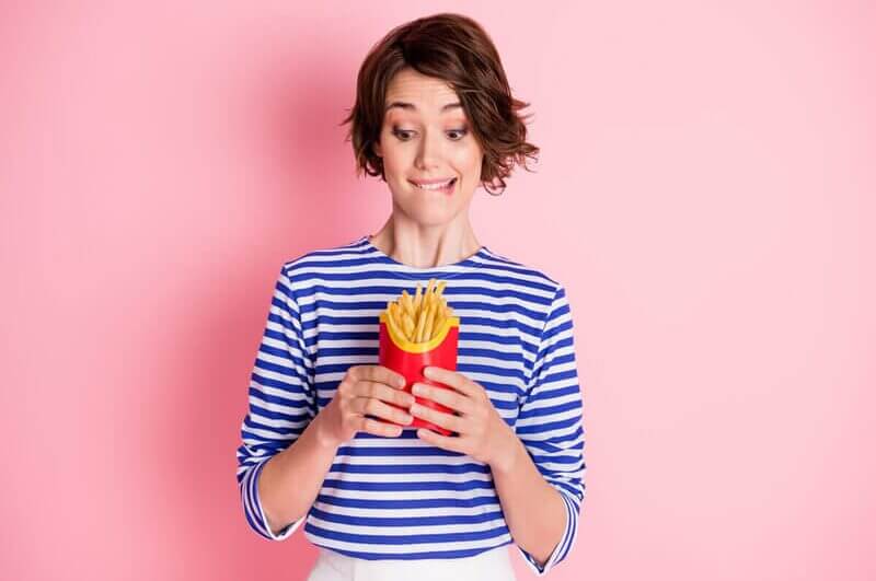 Mulher segurando e olhando para batatas-fritas