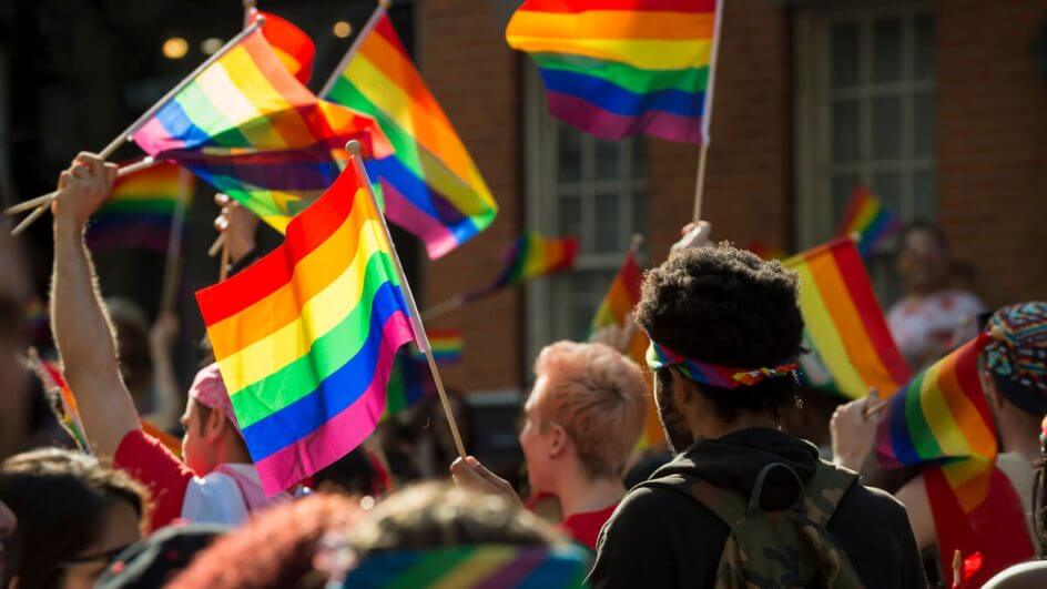 Pessoas com a bandeira da comunidade LGBTQIA+