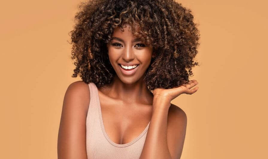 Mulher com cabelo cacheado e iluminado na altura do ombro