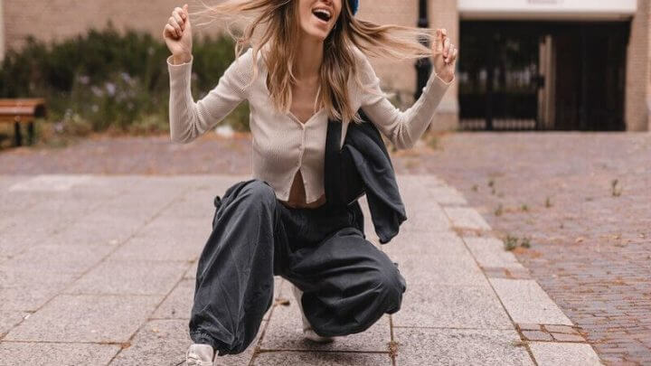 Mulher sorrindo segurando os cabelos e vestindo calça cargo