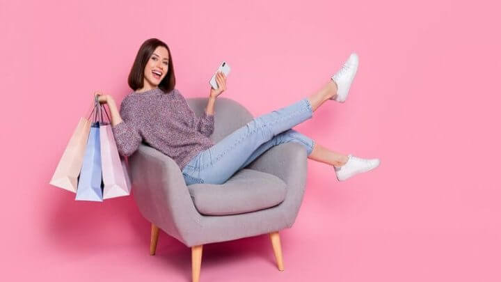 Mulher sentada sorrindo segurando sacola de compras