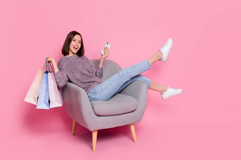 Mulher sentada sorrindo segurando sacola de compras