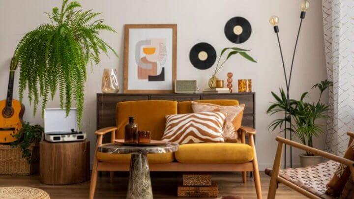 Espaço vintage e aconchegante de sala de jantar com moldura de pôster mock up, sofá amarelo, mesa de centro de madeira, violão, plantas, cômoda, decoração e acessórios pessoais
