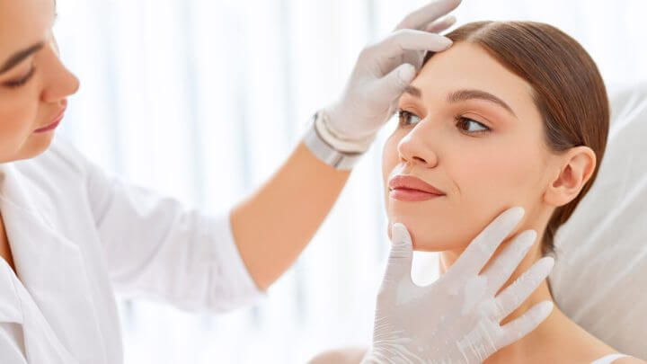 Médica dermatologista examinando rosto de paciente