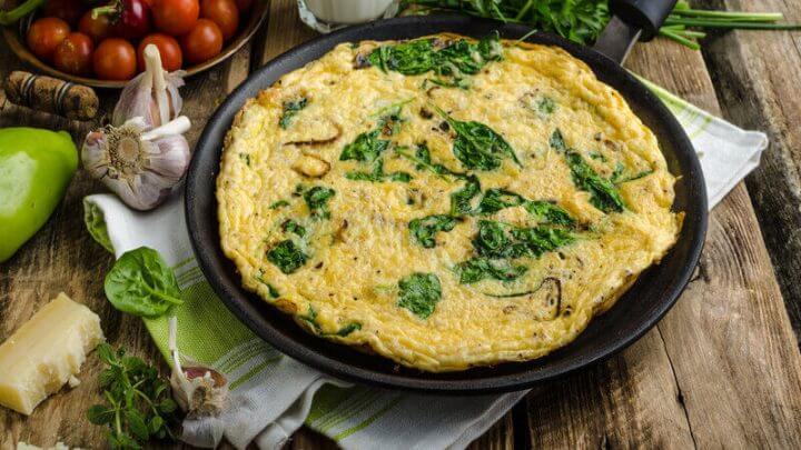 Frittata com espinafre em cima de uma frigideira preta