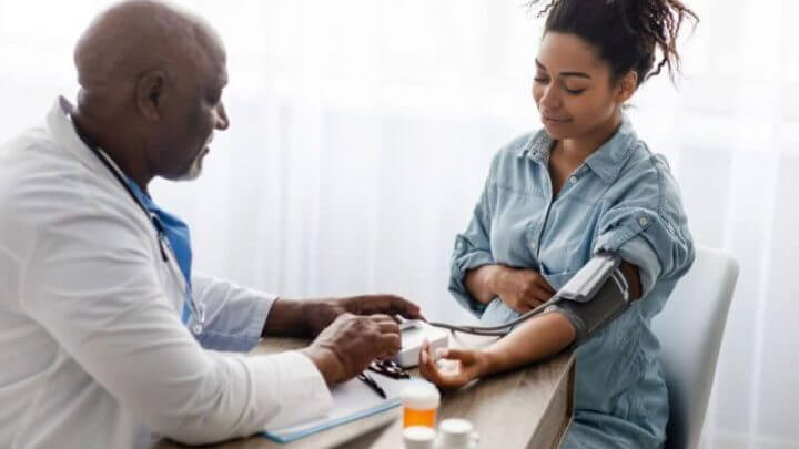Médico medindo pressão arterial de uma mulher grávida