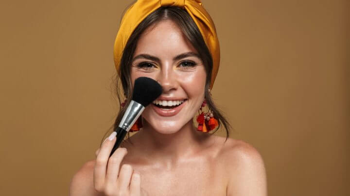 Mulher de bandana amarela com pincel de maquiagem