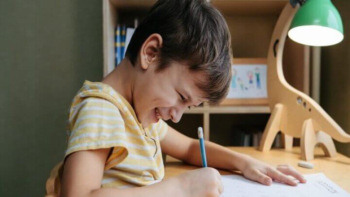 Menino sorrindo sentado estudando