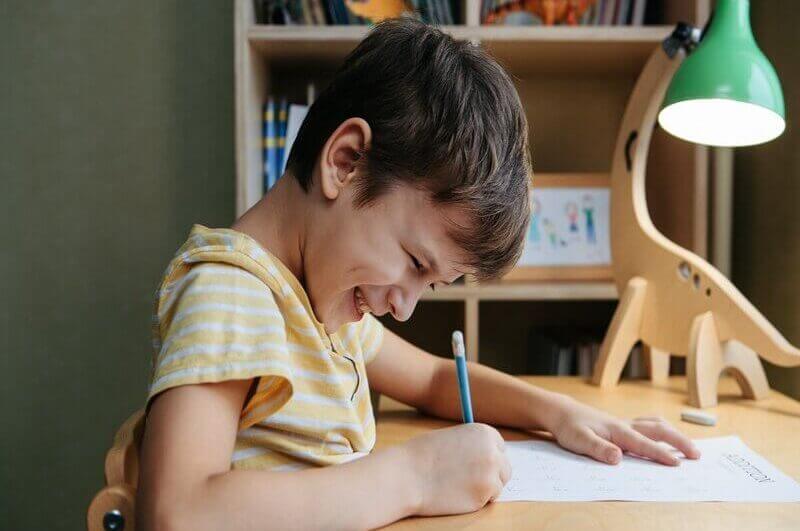 Menino sorrindo sentado estudando