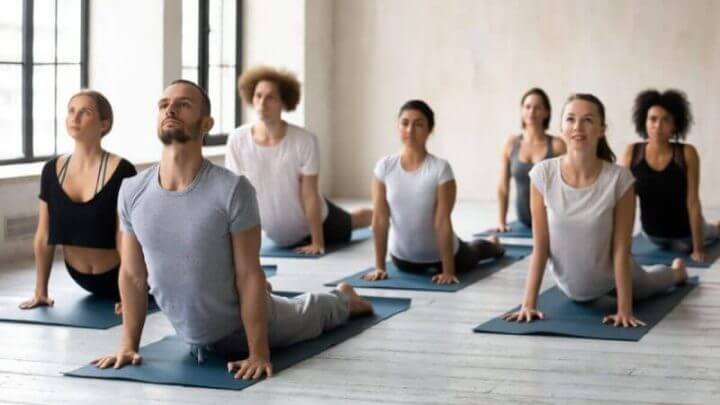 Pessoas em salda fazendo pilates em tapete cinza