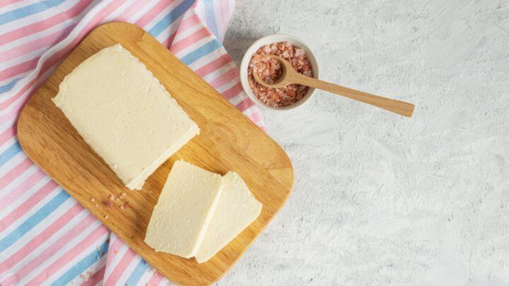 Queijo de tofu cortado em tábua de madeira ao lado de especiarias