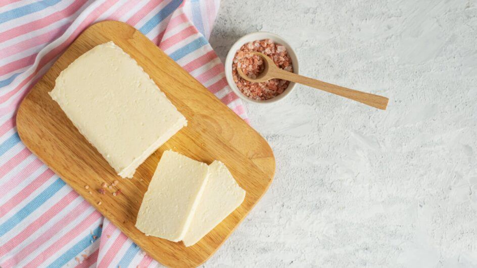 Queijo de tofu cortado em tábua de madeira ao lado de especiarias