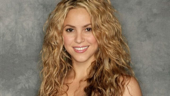 Shakira de cabelos loiros e ondulados sorrindo