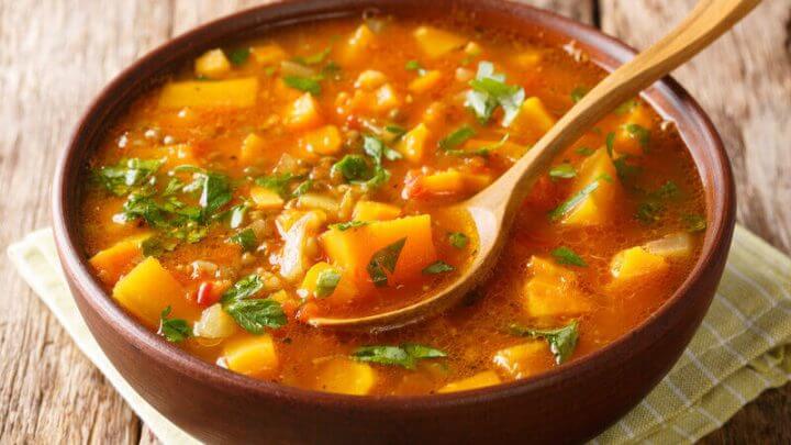 Recipiente marrom com sopa de batata-doce polvilhada com coentro