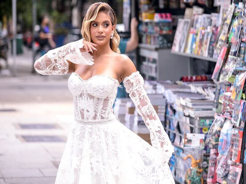 Mulher com vestido de noiva em frente a uma banca de jornal