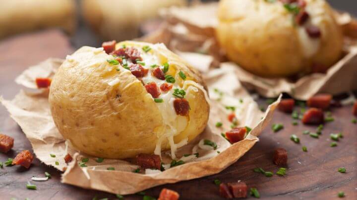 Batata recheada com queijo, bacon e cebolinha em cima de papel