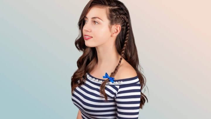Menina com cabelo solto e trança lateral e blusa preta e branca de listras