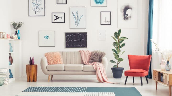 Cadeira vermelha e tapete azul perto de sofá no interior da sala de estar colorida com figuras estampadas na parede