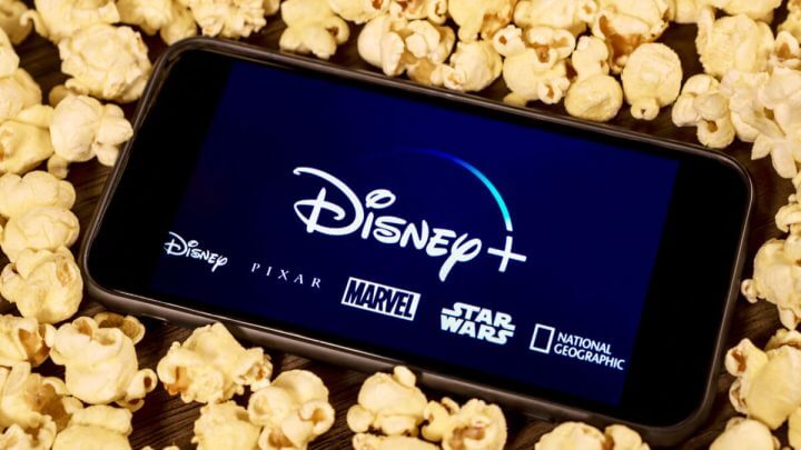 Celular com imagem da Disney+ com várias pipocas ao redor