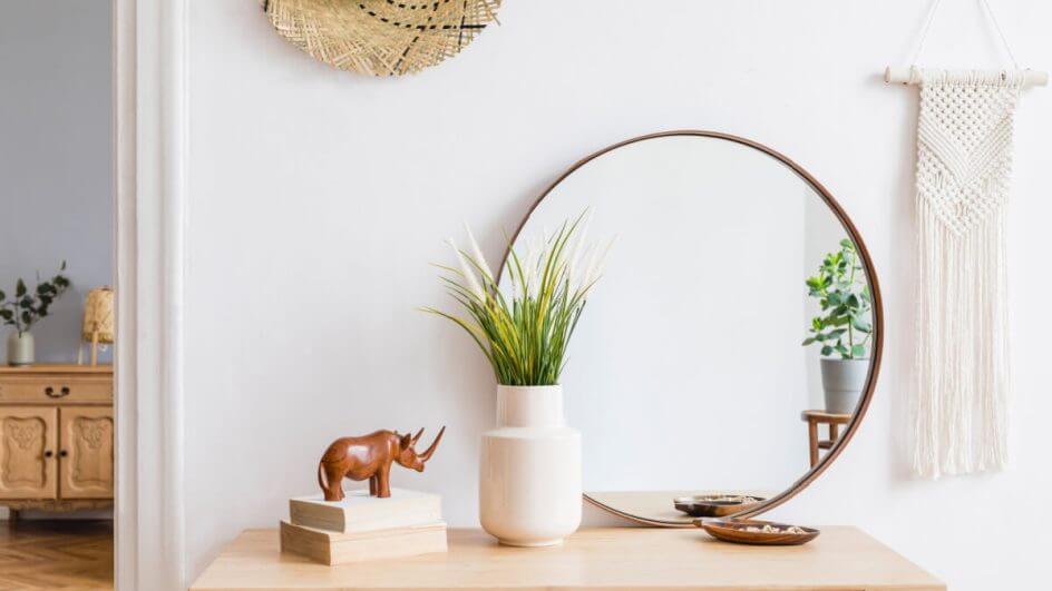 Mesa com objetos decorativos: espelho, vaso, rinoceronte e outros