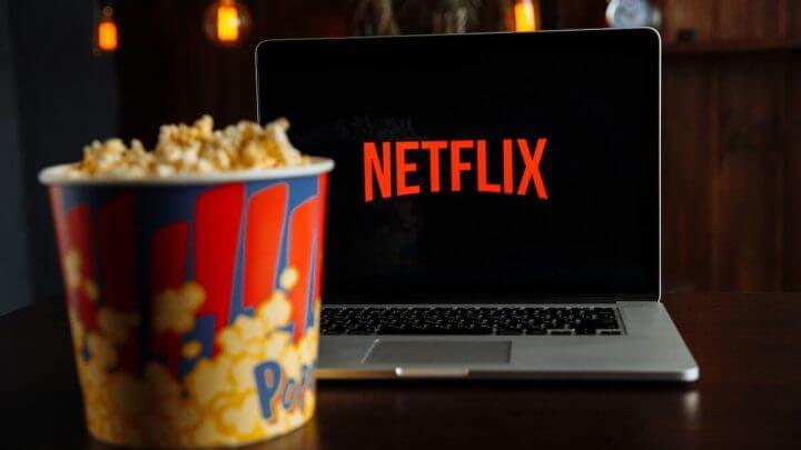 Logo da Netflix em uma televisão e um balde de pipoca em cima de uma mesa