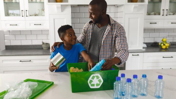 Pai e filho na cozinha conversando e separando lixo para reciclagem