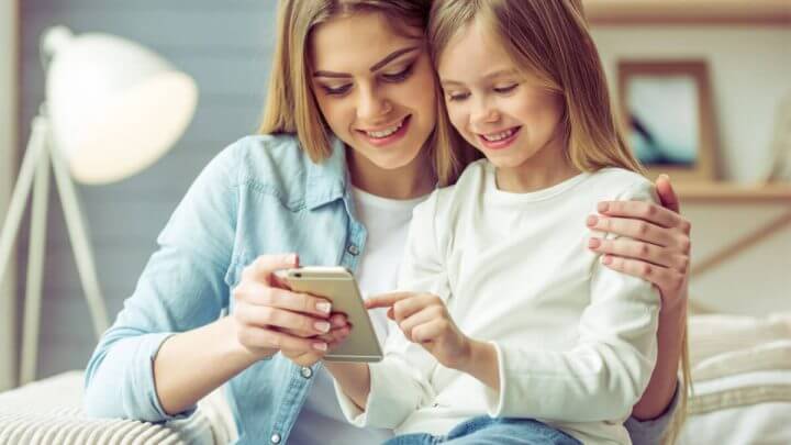 Mãe jovem e sua filhinha estão usando um smartphone