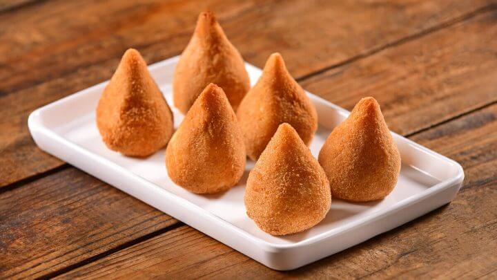 Seis coxinhas assadas servidas em louça branca