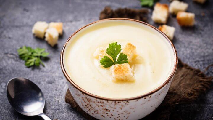 Creme branco em recipiente com coentro e pedaços de pão