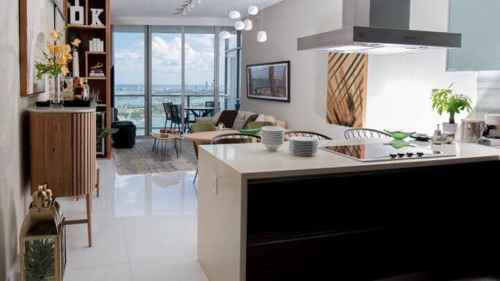Cozinha com ilha no centro, janela de fundo, sofá e quadros na parede