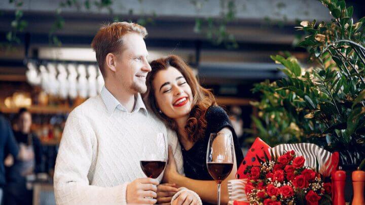 Homem e mulher abraçados e sentados tomando vinho