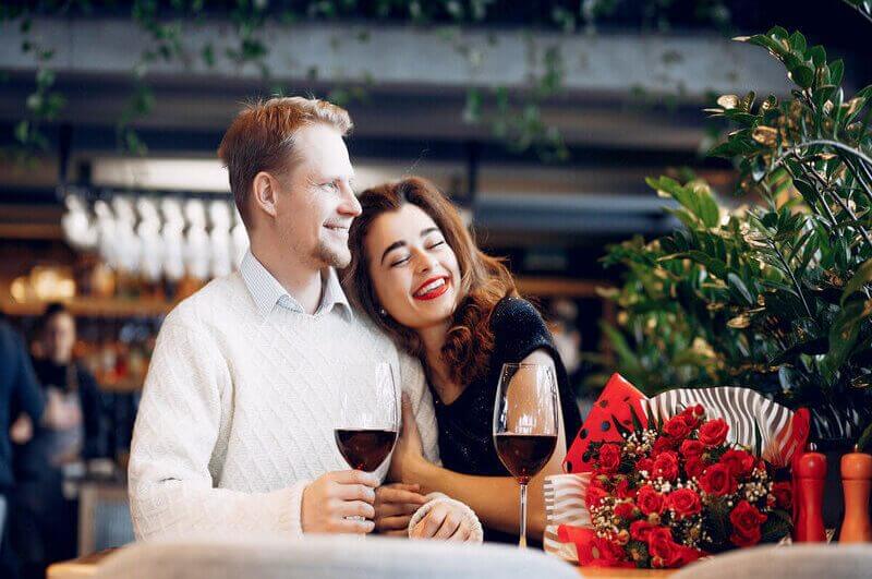 Homem e mulher abraçados e sentados tomando vinho