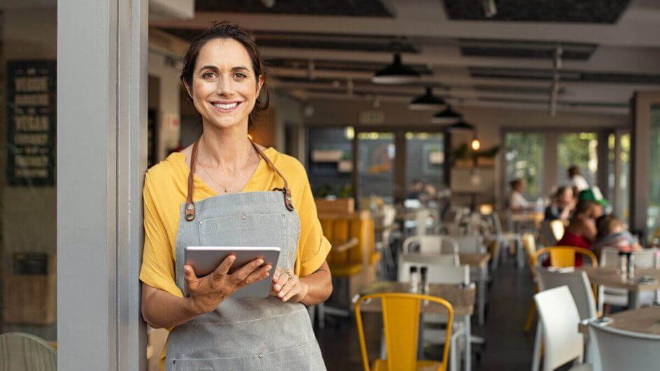 Mulher de blusa amarela em pé segurando tablet