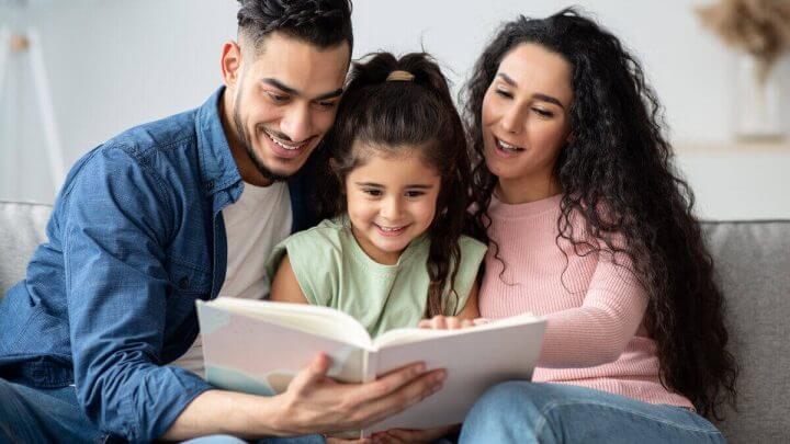 Homem e mulher lendo livro para uma menina
