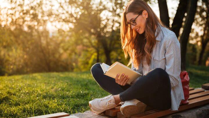 Mulher sentada em um parque lendo livro