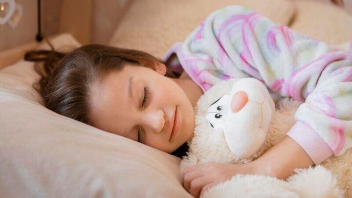 Meninas segurando urso de pelúcia e dormindo