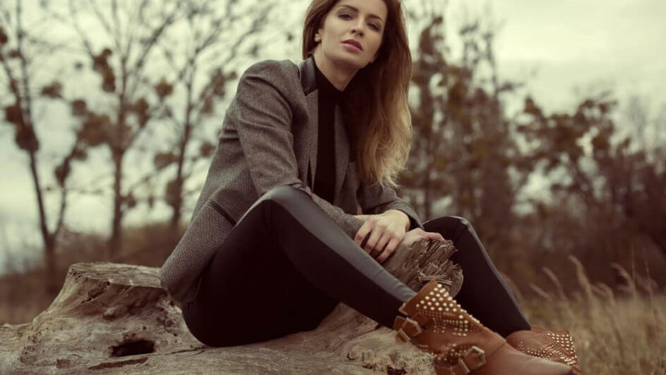 Mulher sentada em uma pedra ao ar livre e usando uma bota western